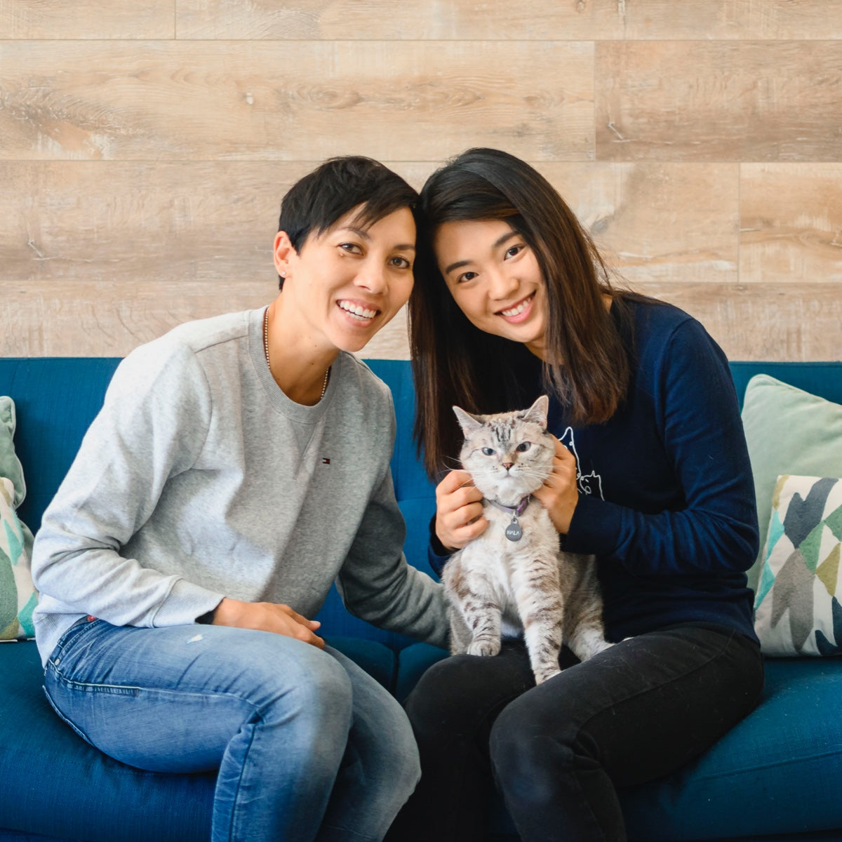 two people holding a cat on blue couch